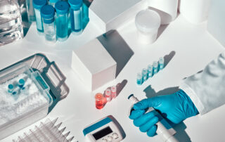 Lab equipment for PCR testing sits on top of a white table with a gloved hand in the shot